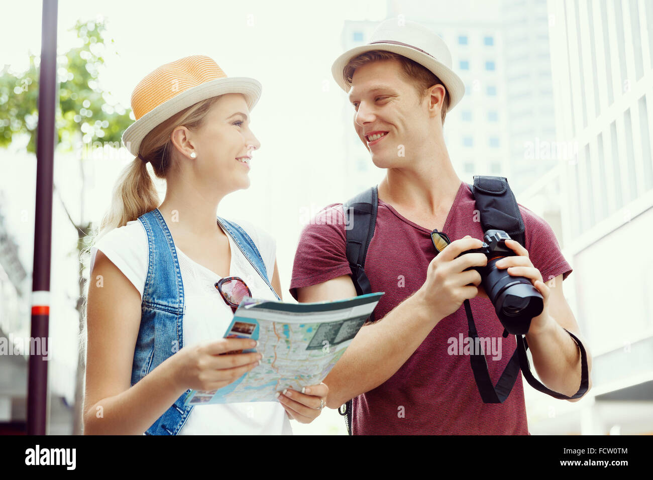 Happy young couple as tourists with a map Stock Photo - Alamy
