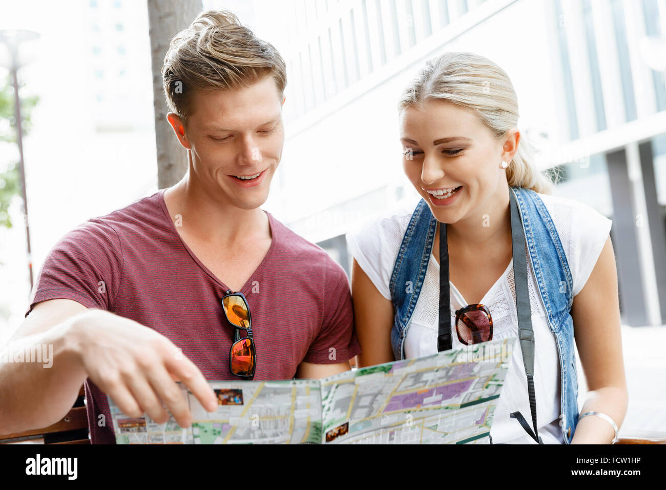 Happy young couple as tourists with a map Stock Photo - Alamy
