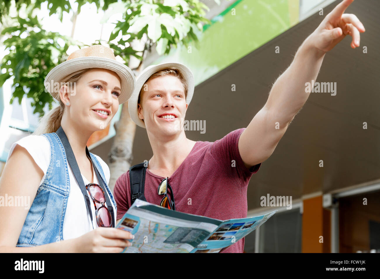 Happy young couple as tourists with a map Stock Photo - Alamy