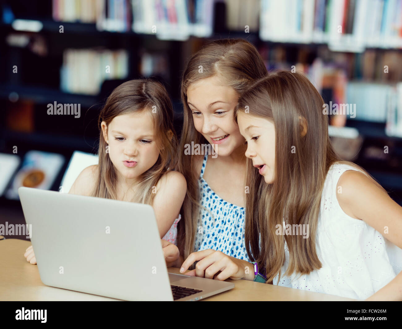 Little girls with a laptop in library Stock Photo - Alamy