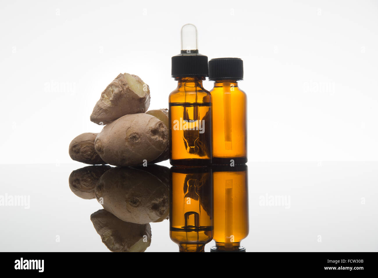 ginger essential oil in amber bottle with fresh ginger root and dropper Stock Photo
