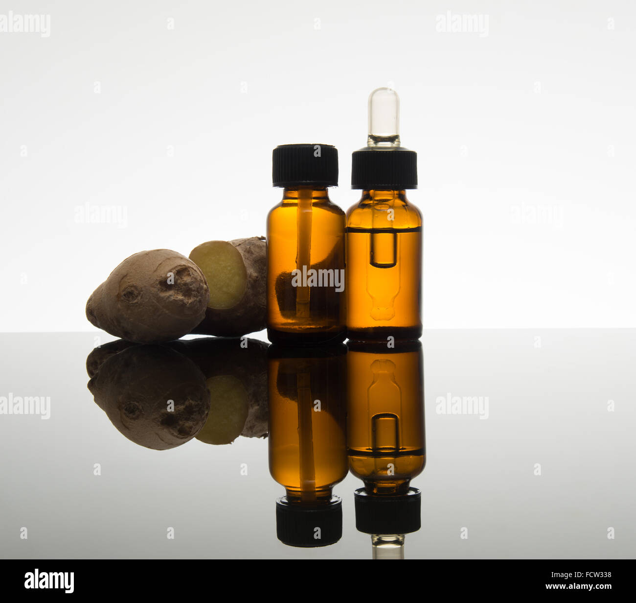 ginger essential oil in amber bottle with fresh ginger root and dropper Stock Photo