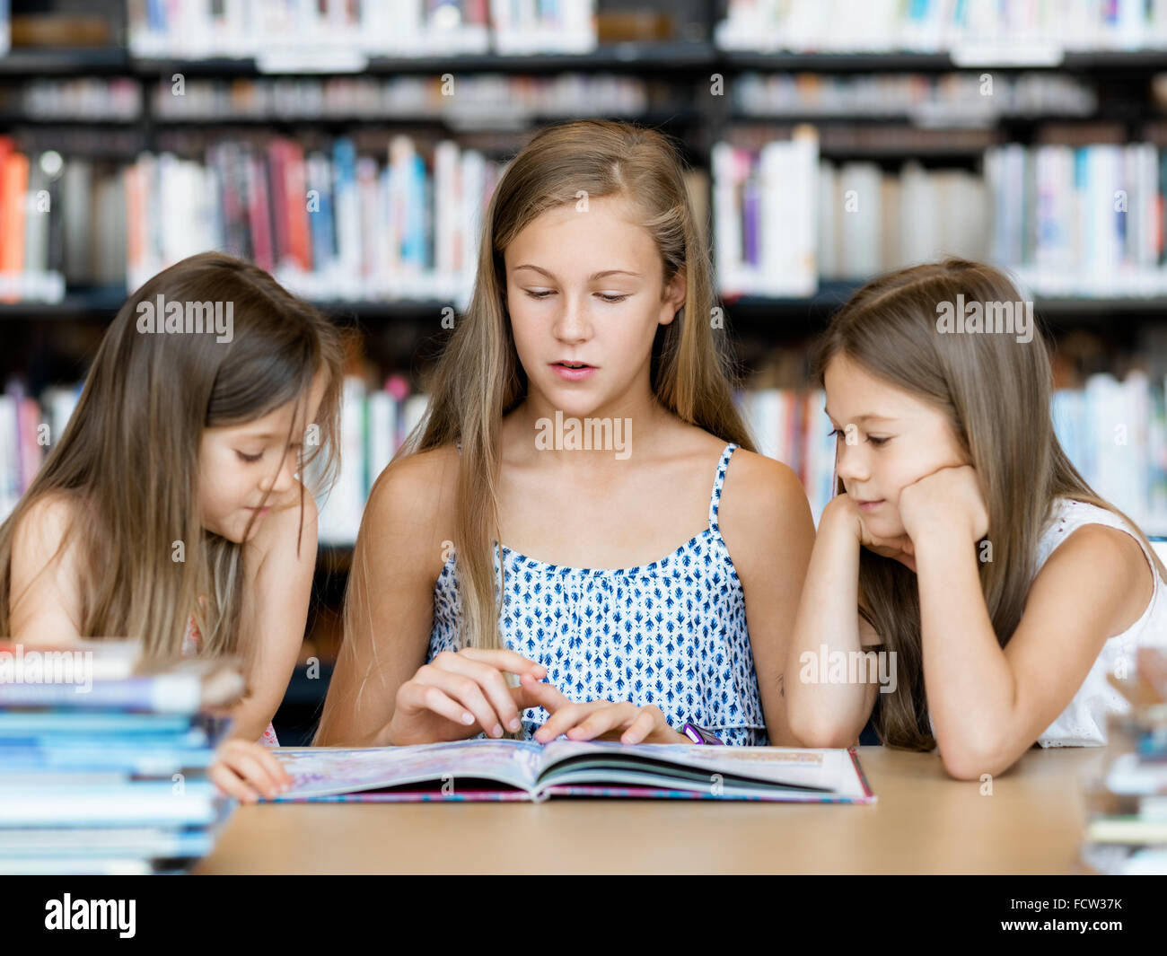 Little girls reading books in library Stock Photo - Alamy