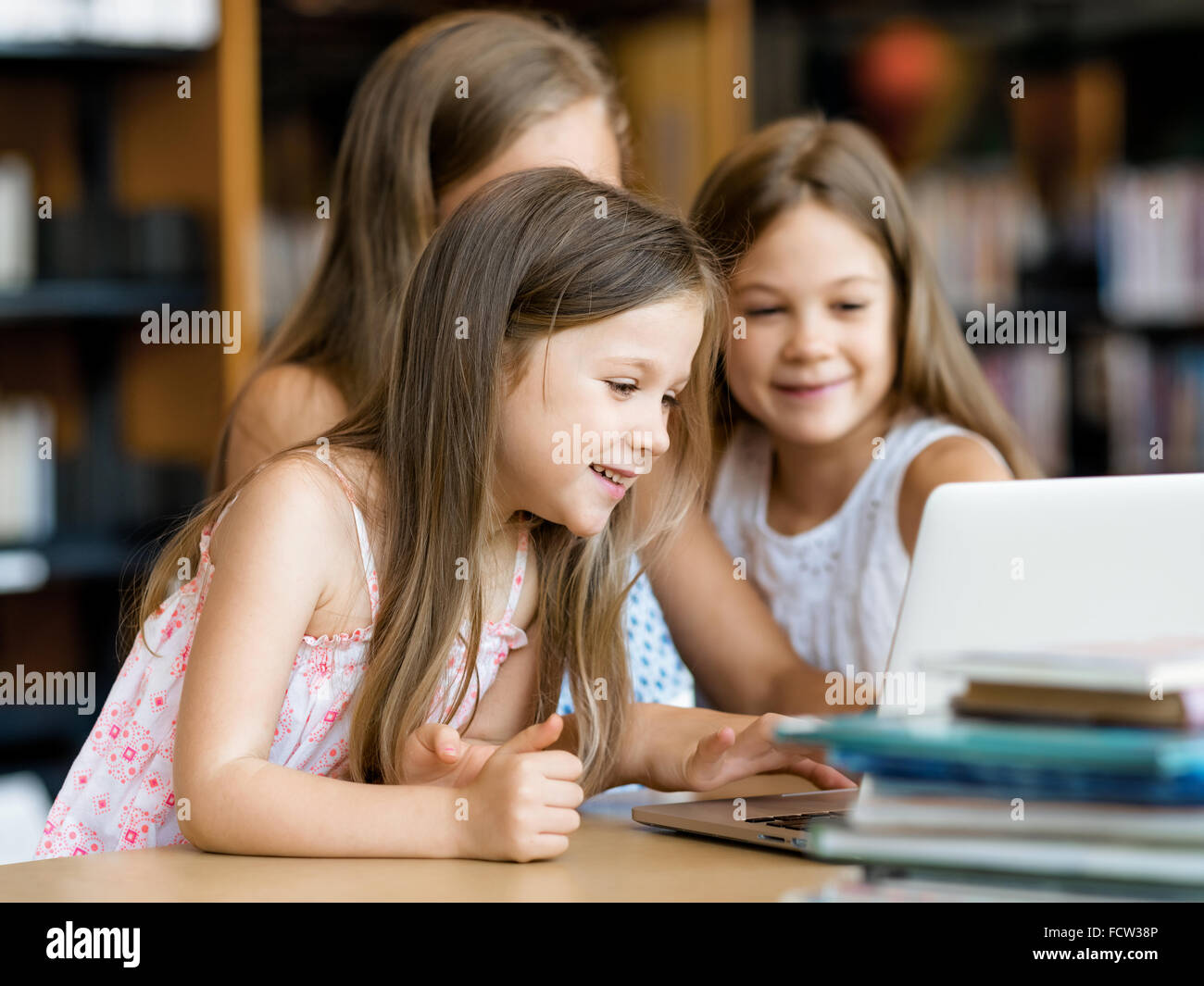 Little girls with a laptop in library Stock Photo - Alamy
