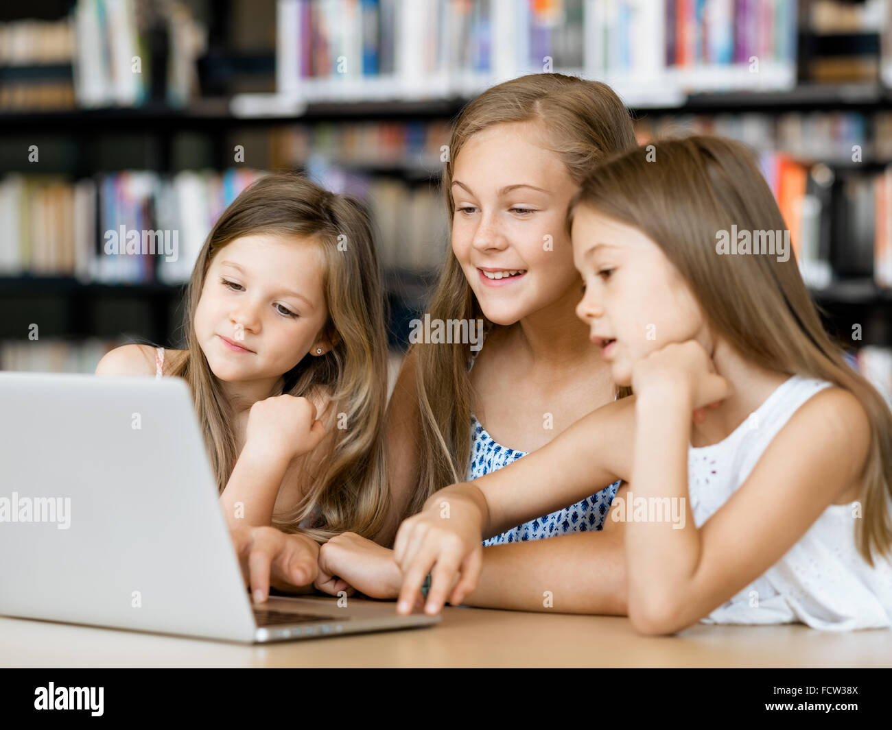 Little girls with a laptop in library Stock Photo - Alamy