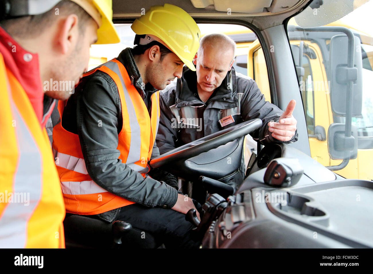 Driving instructor Sylvio Hanke (R) explains the cockpit of a 40-ton lorry to asylum seekers Mustafa al Amir (C) and Basel Jaghssi in Halle/Saale, Germany, 25 January 2016. The construction company Guenter Papenpurg intends to train around 100 refugees to help them become professional drivers. The company also plans to offer training for concrete workers, building machine operators and construction helpers to asylum seekers. 30 refugees are already currently completing an internship with a focus on 'Learning the German language'. Photo: JAN WOITAS/dpa Stock Photo