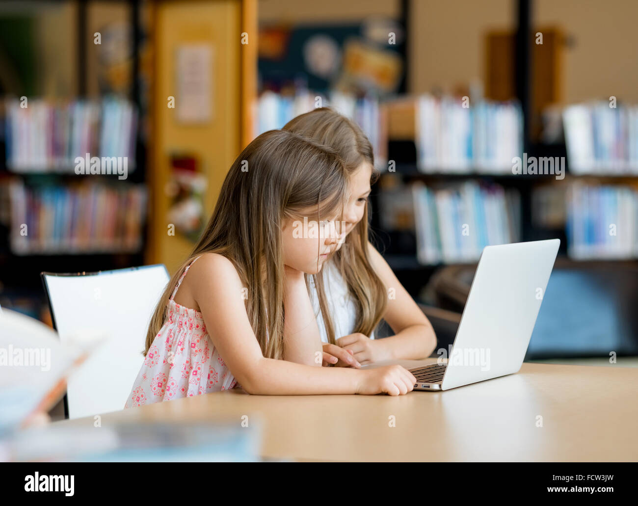 Little girls with a laptop in library Stock Photo - Alamy
