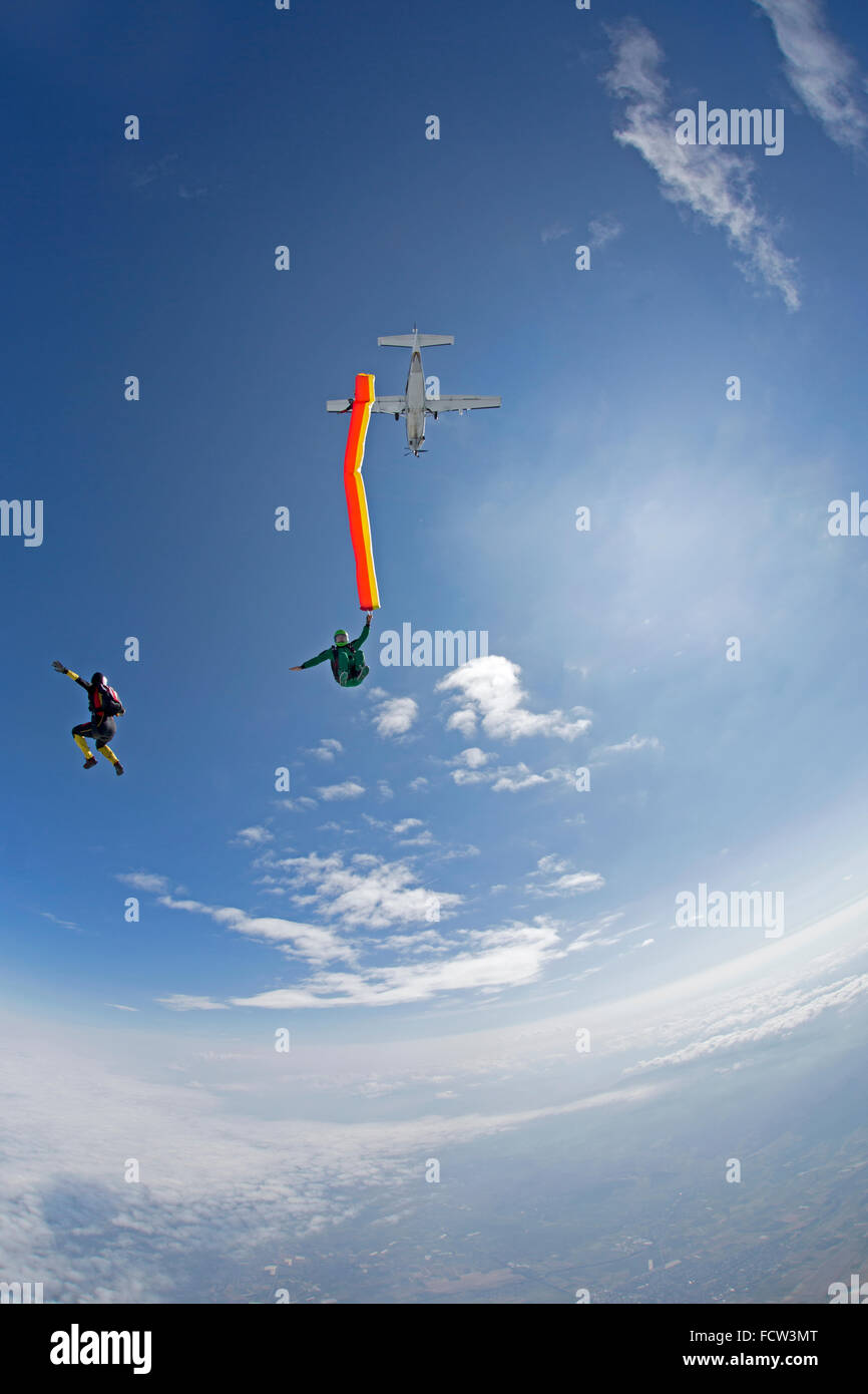 A crazy freefly skydiving team is playing hard with an air-tube in freefall. Thereby all are jumping from a plane together. Stock Photo