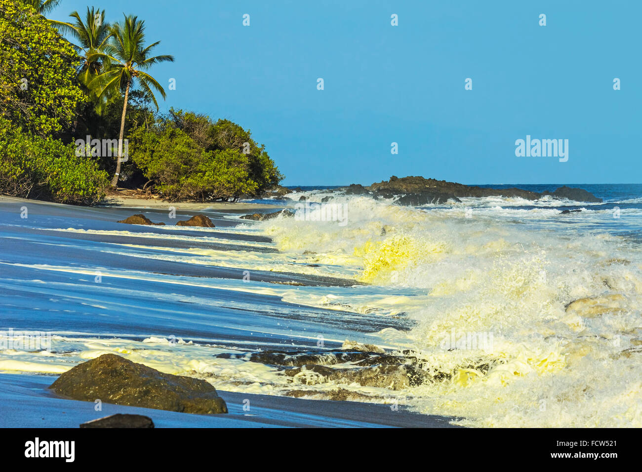 Surf & yellow algal bloom on Montezuma Beach at this resort on Nicoya Peninsula's SE tip; Montezuma, Puntarenas, Costa Rica Stock Photo
