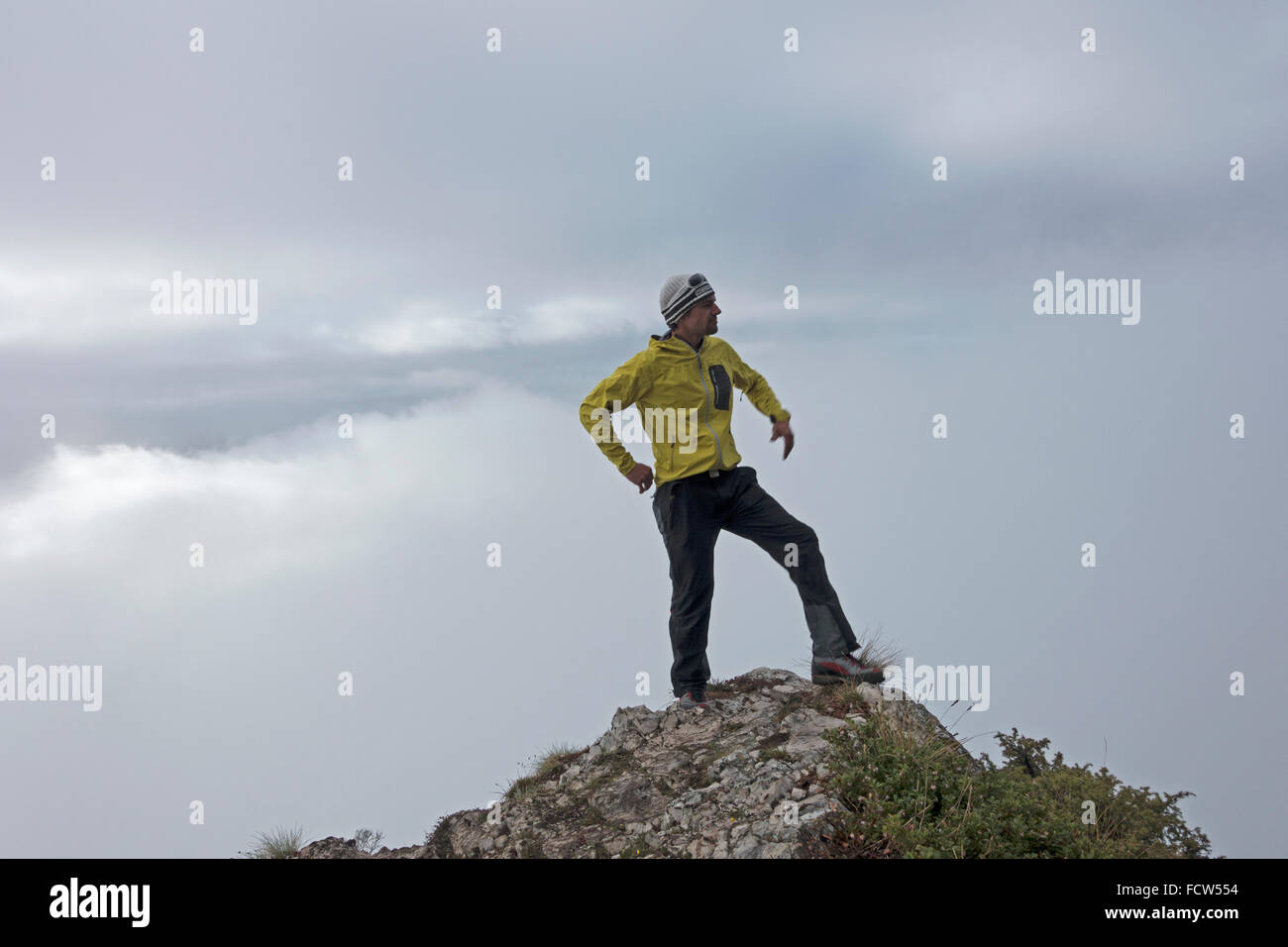 BASE jumper is standing on the edge of a cliff and looking out for the better weather. Because right now is foggy and not jumpable. Stock Photo