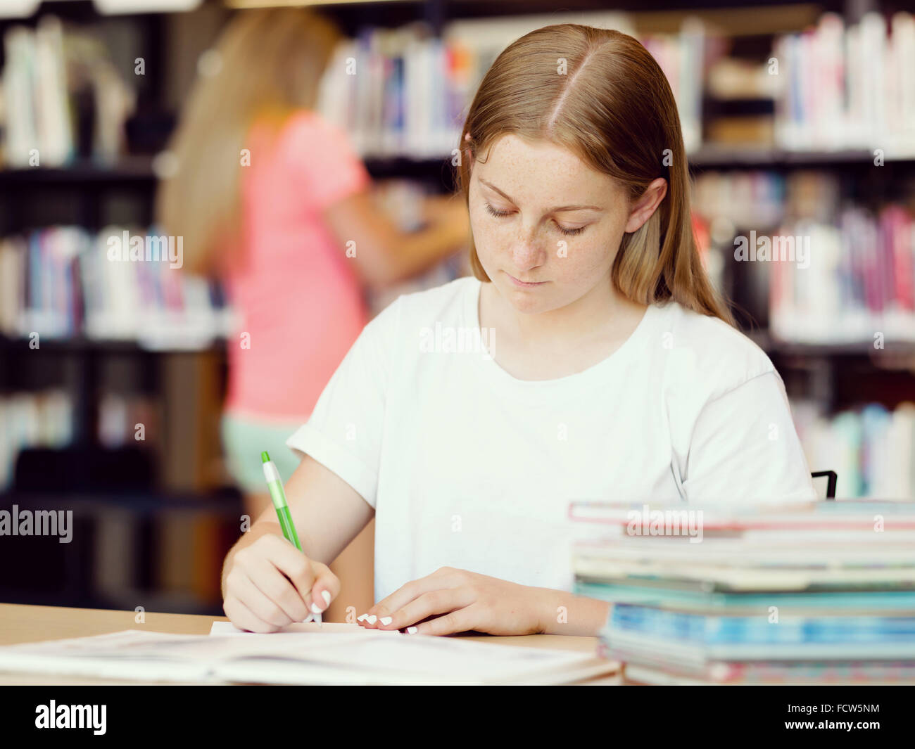 Teenage girl with books studying in library Stock Photo - Alamy