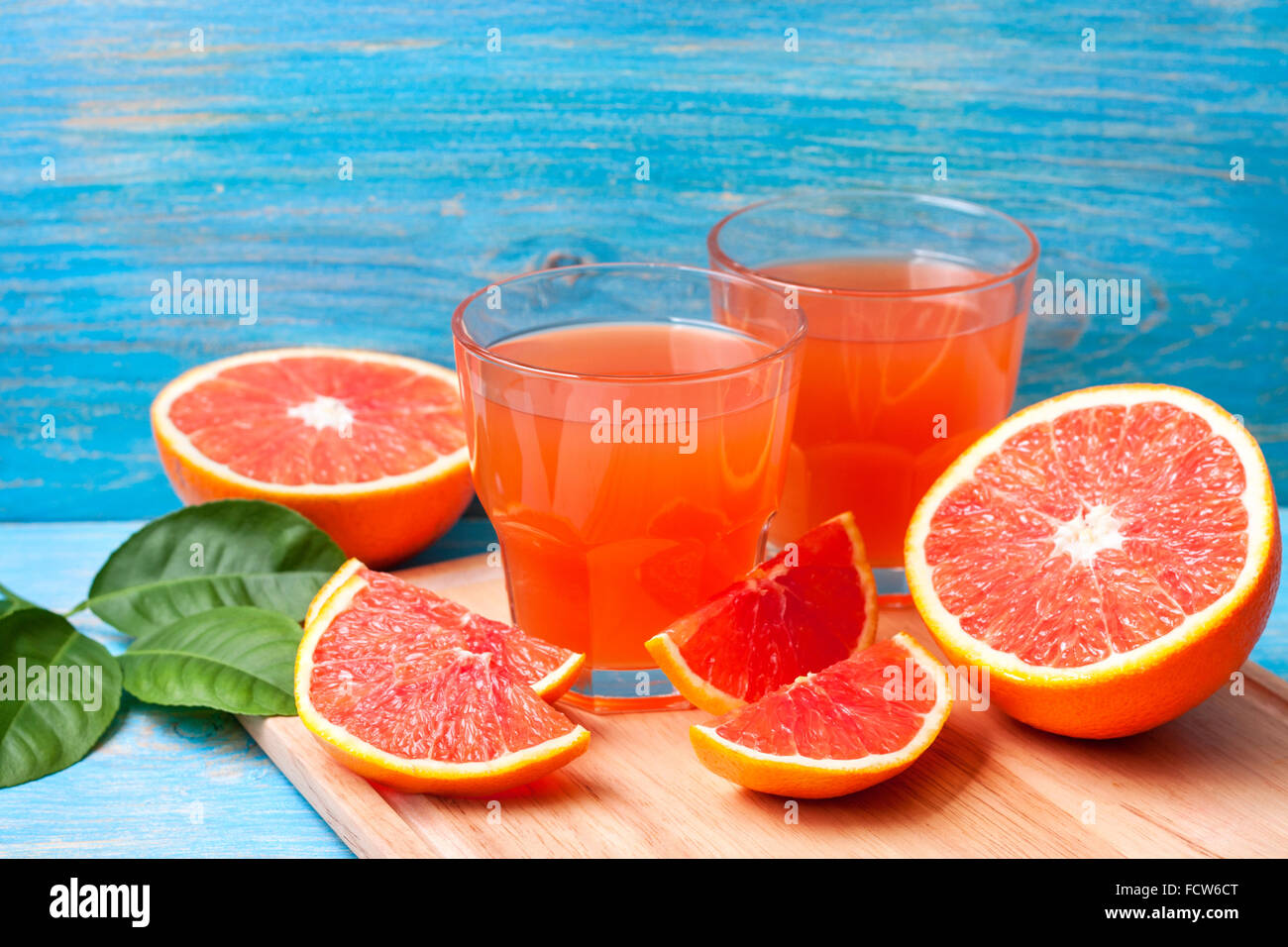 Grapefruit juice and fresh grapefruit on a blue wooden background Stock Photo