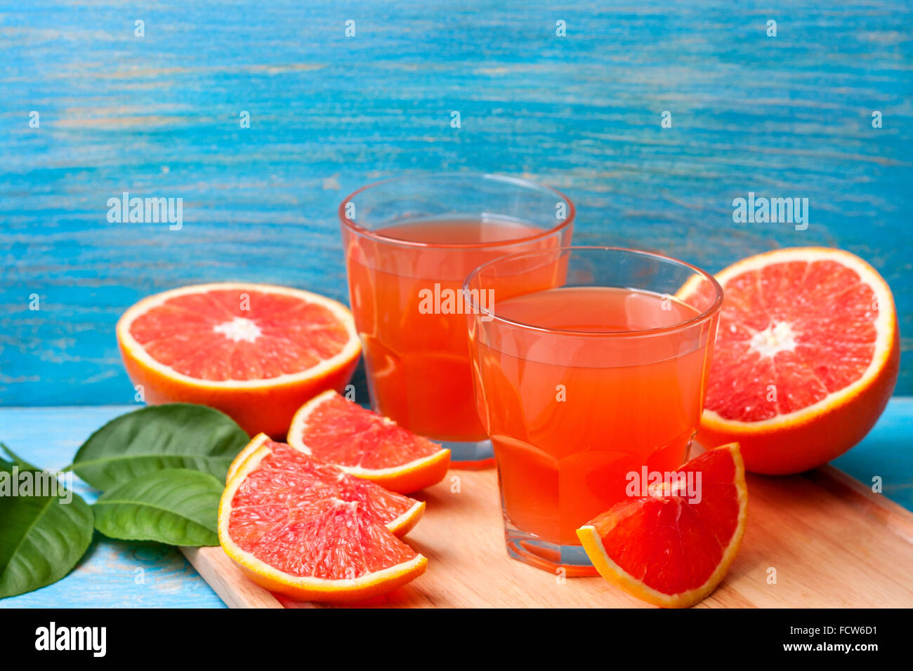Grapefruit juice and fresh grapefruit on a blue wooden background Stock Photo