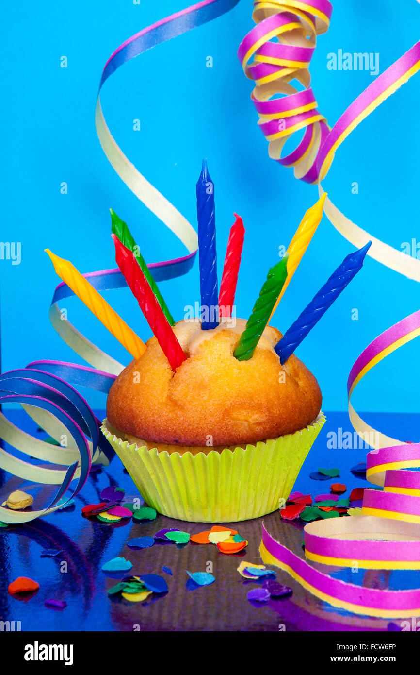 Birthday cupcake with lots of candles, party streamers and colorful