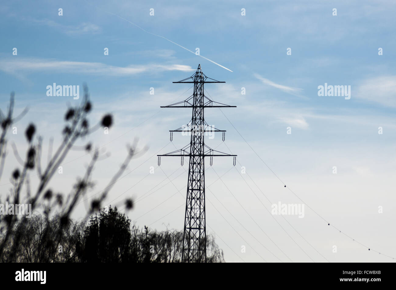 high-voltage electricity pylons against blue sky with clouds Stock Photo