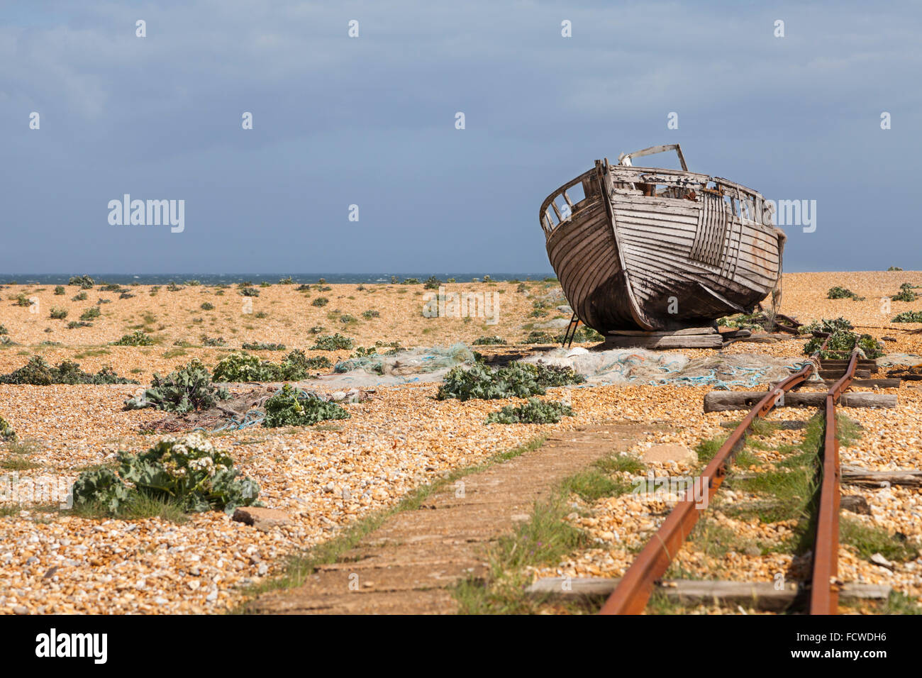 Abandoned old fishing boat and transport tracks on the shingle beach at ...