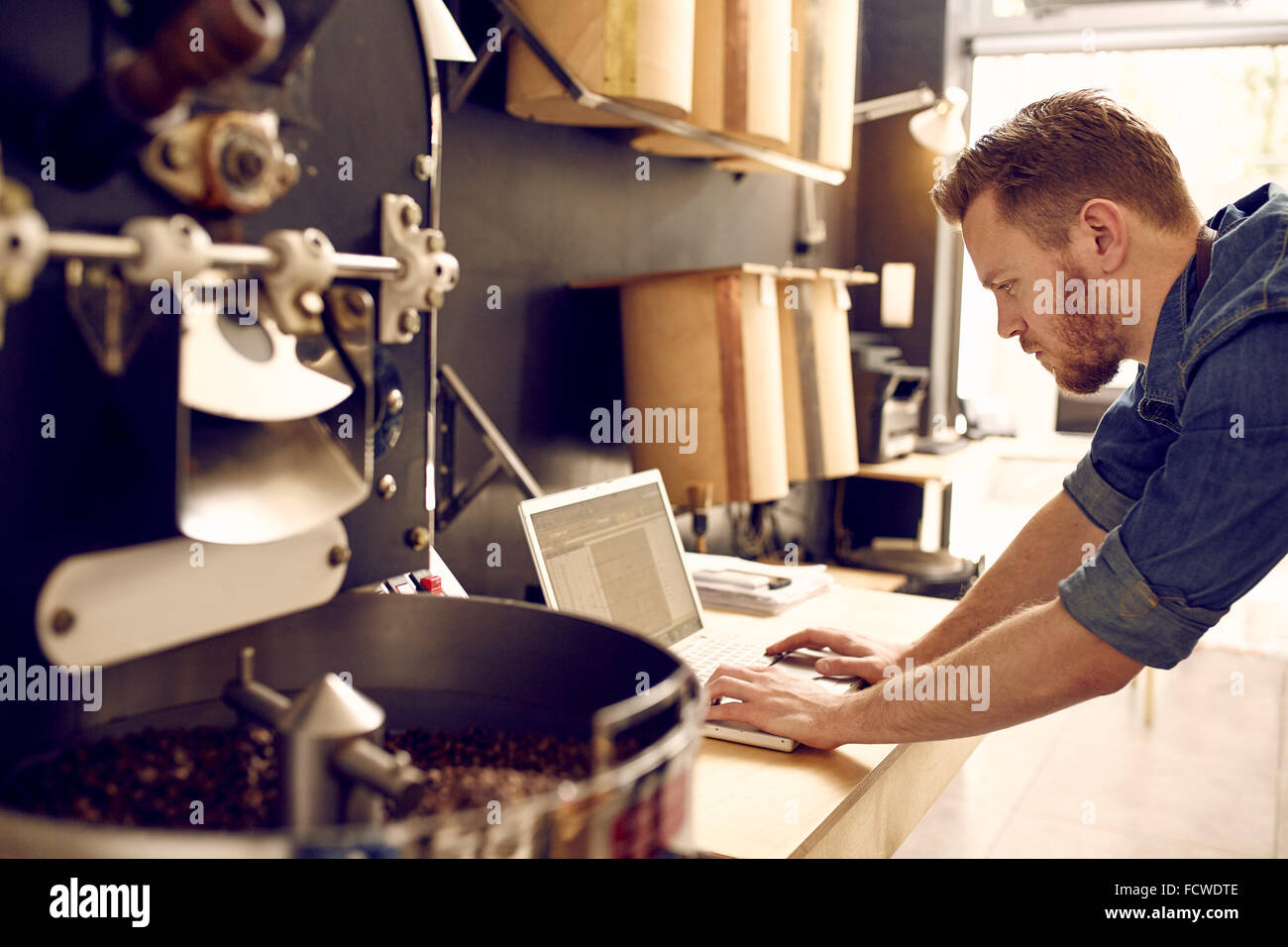 Business owner of a coffee roastery checking his laptop Stock Photo