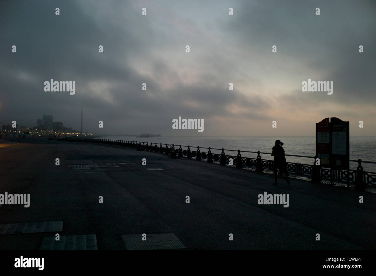 Silhouette of runner on empty promenade under stormy morning sky Stock Photo
