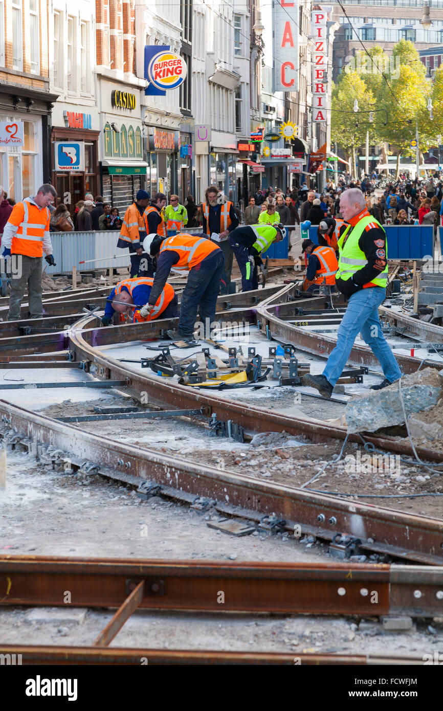 Workers lay / laying / building / working on new tram tracks on a road / highway construction site in Amsterdam, The Netherlands. (78) Stock Photo