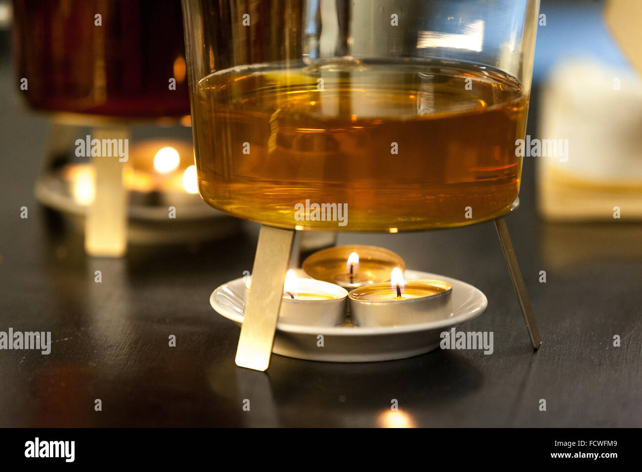 Burning candle warming the teapot Stock Photo