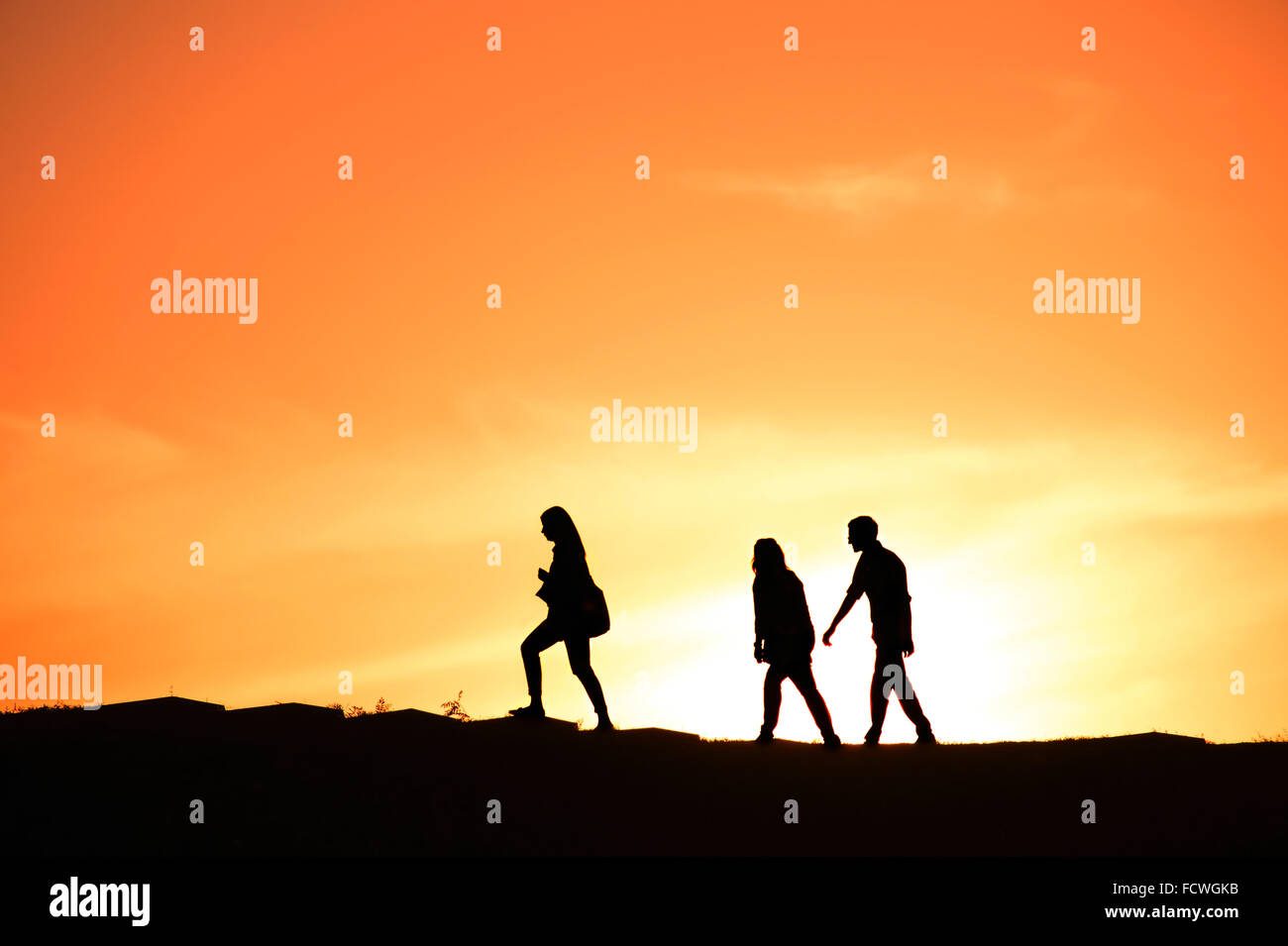 SIlhouette of a group of people walking at sunset on a hill Stock Photo ...