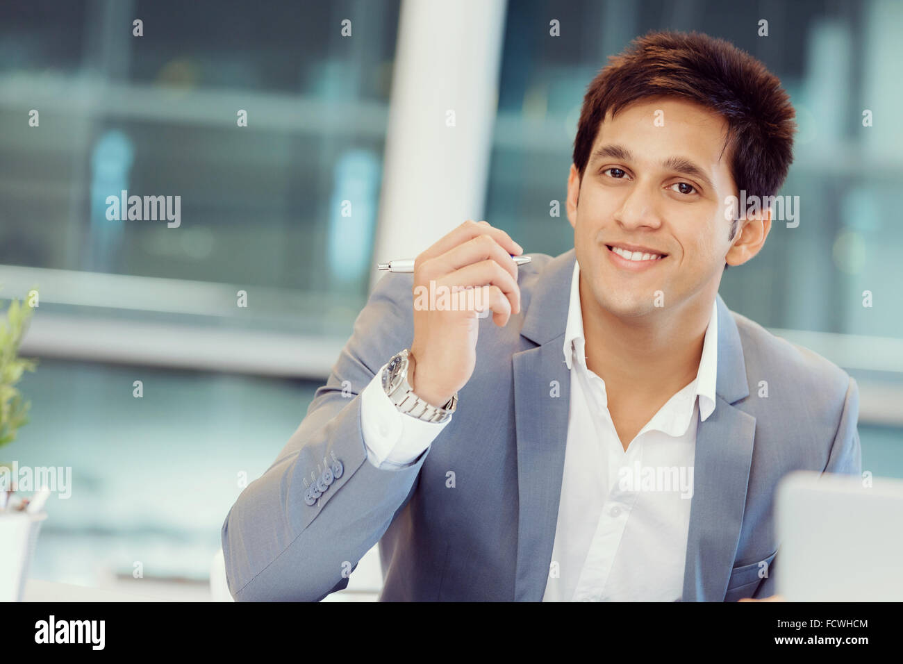 Businessman standing in office smiling at camera Stock Photo - Alamy