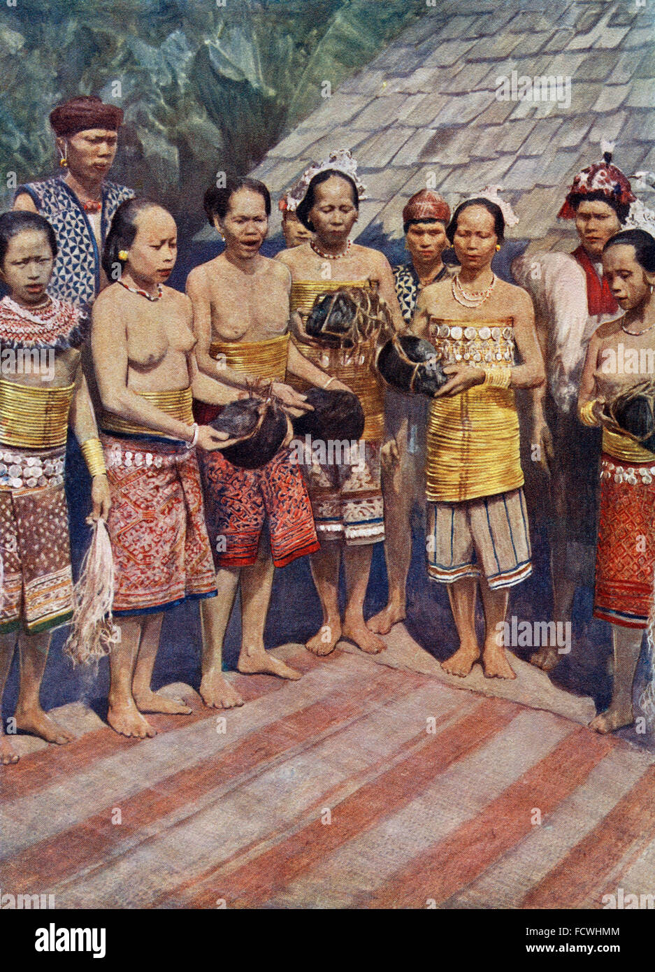 Dayak, Dyak or Dayuh women of Borneo, south east Asia, dancing with human heads.  A few days after the return of a successful head-hunting expedition, the heads, which had been hacked off the dead bodies, were brought into the house. Then followed a time of rejoicing in the course of which the heads were taken by the women who, having performed fantastic dances, hung them beside the old ones.  The presence of heads in the house was supposed to attract the benevolent spirits who lived around them. Stock Photo