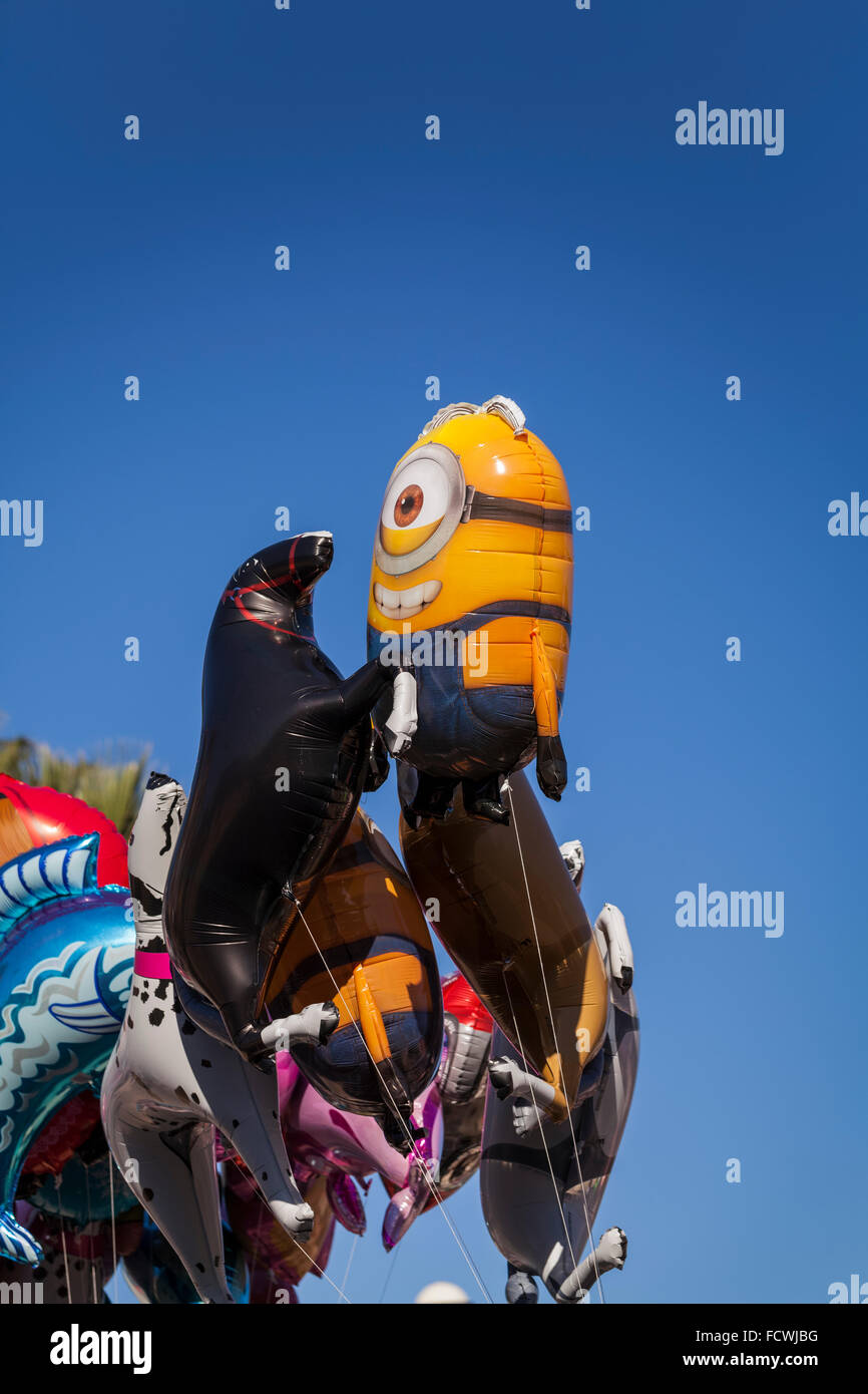 Helium filled balloons in shapes of horses and minions float above the