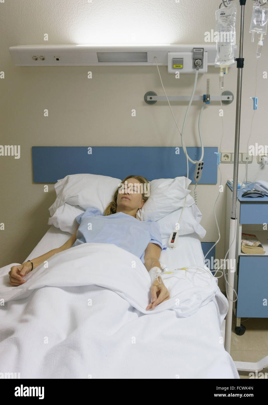 Woman, 35-40 years old, sedated and lying in hospital bed after operation. Stock Photo