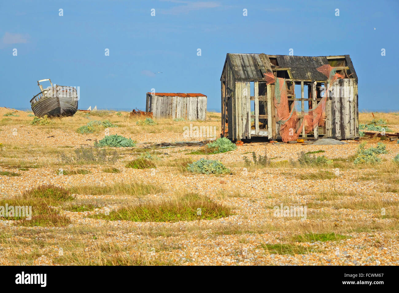 Picturesque old abandoned fishing boat & fishermen's shacks on Dungeness beach, Kent, UK the desolate landscape a favourite location for photographers Stock Photo