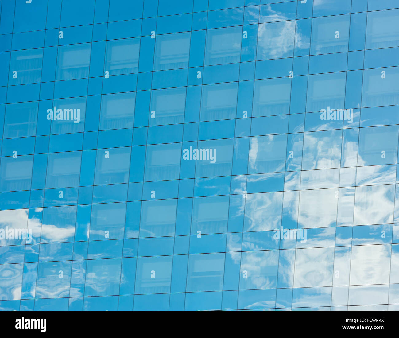 blue sky and clouds reflected in windows of modern office building ...