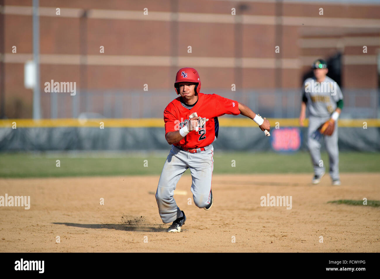 High school runner putting it into gear as he watches ground ball head into left field that allowed him to come around to score. USA. Stock Photo