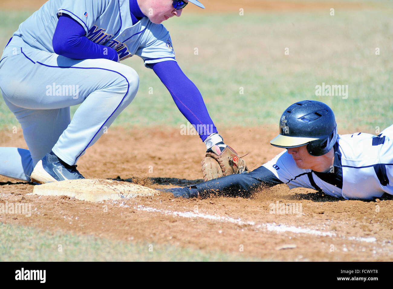 A high school base runner dives back to the first base bag on a pick