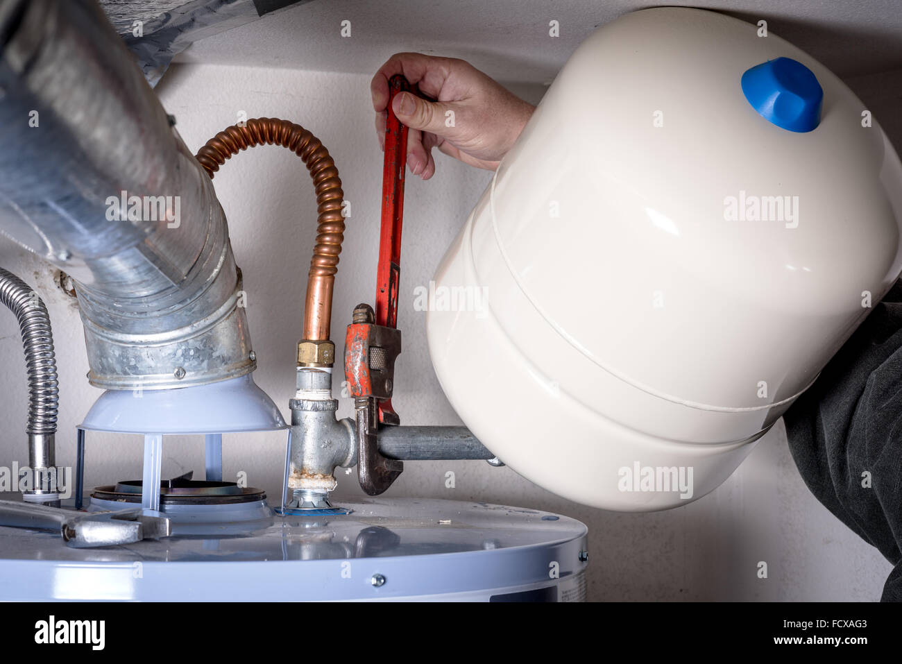 Plumber installs a compression tank on a hot water heater Stock Photo