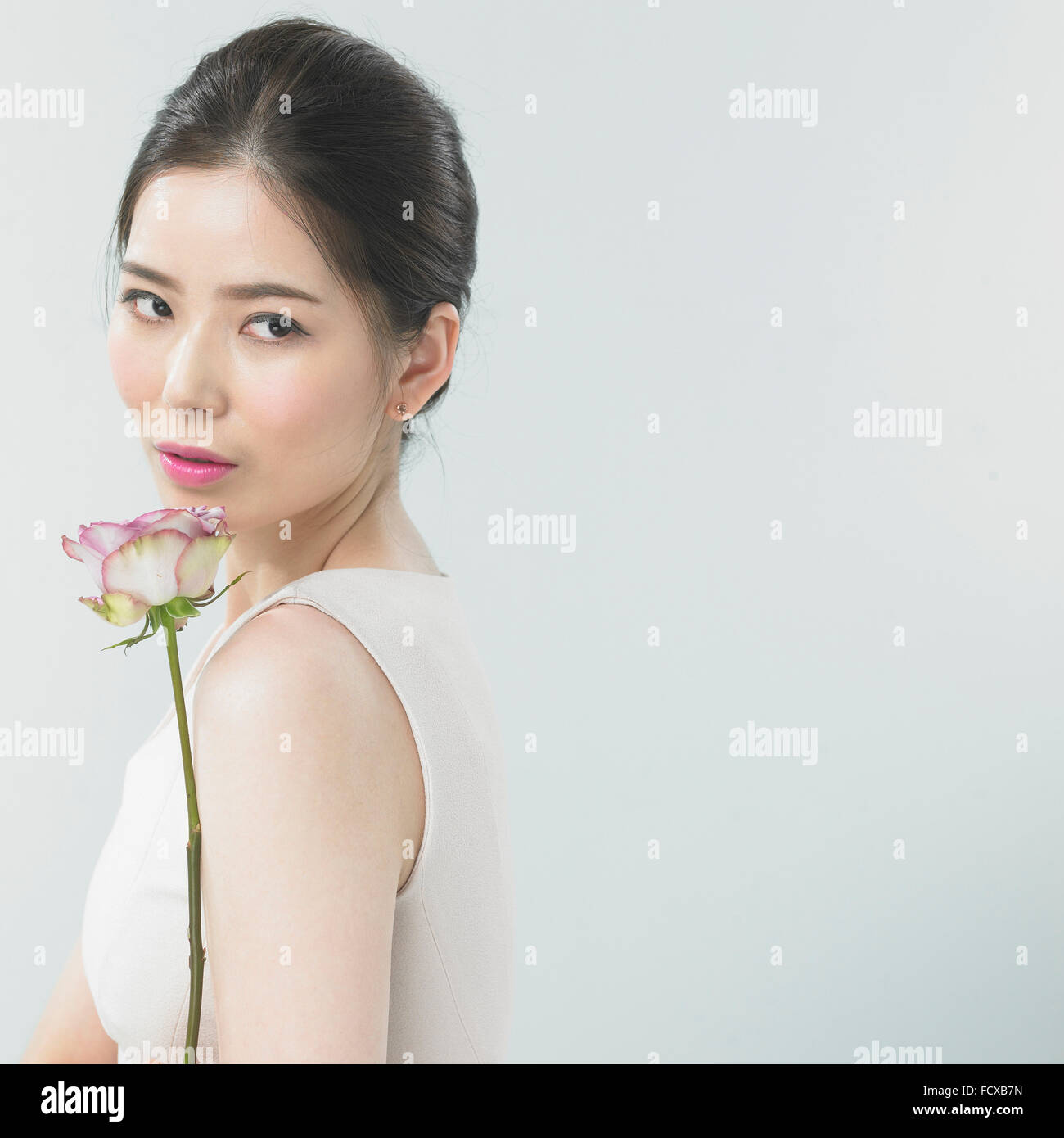 Woman with pink lip make-up with a flower looking aside down Stock Photo