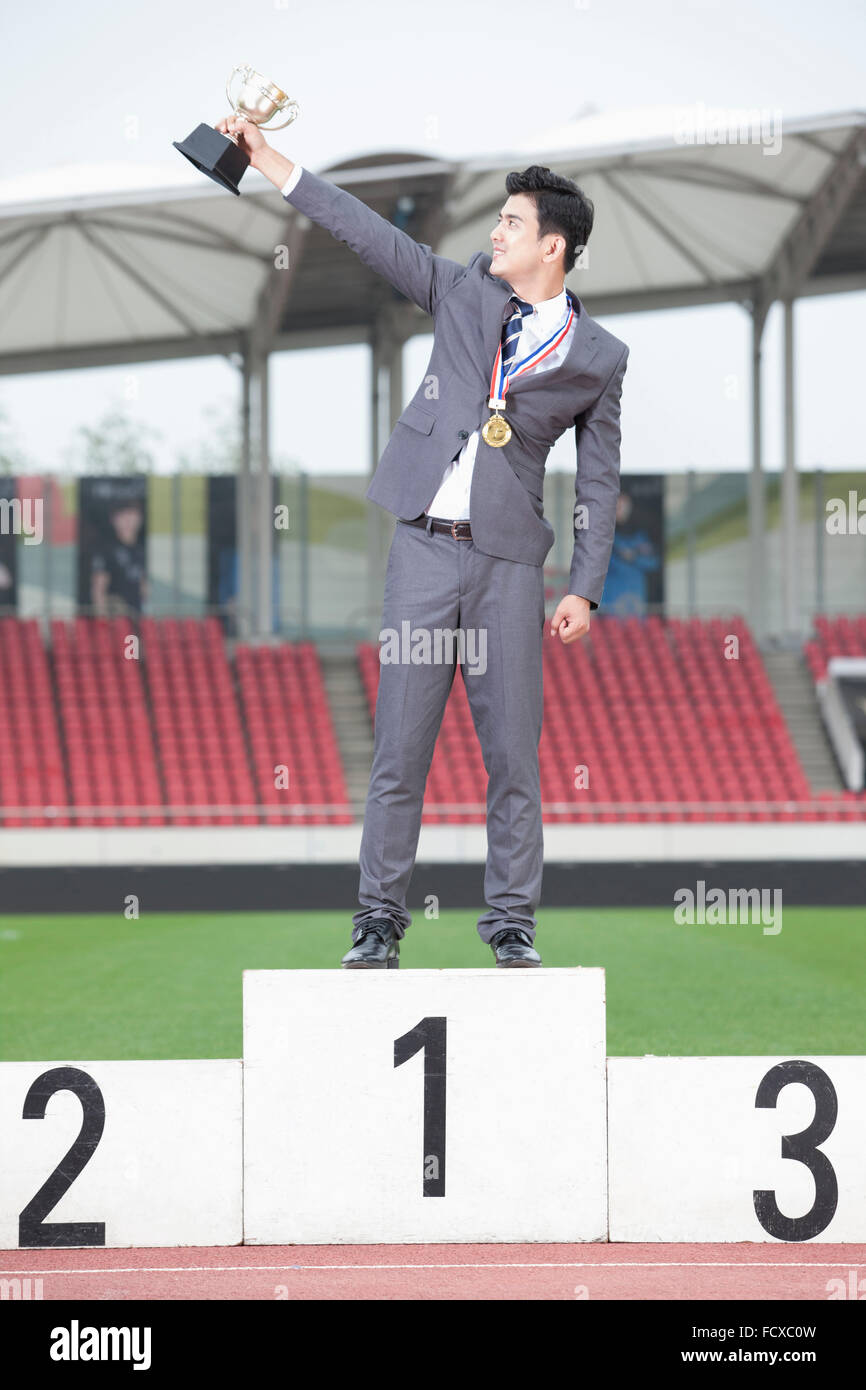 Business man standing on the podium with the first place trophy and a gold medal Stock Photo