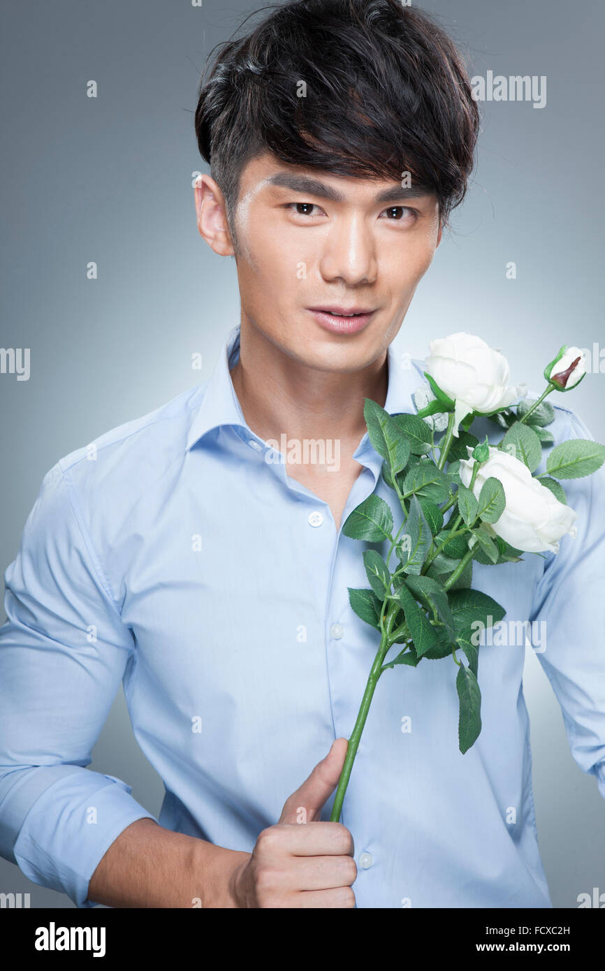 Man in blue shirt holding white flowers and staring forward Stock Photo