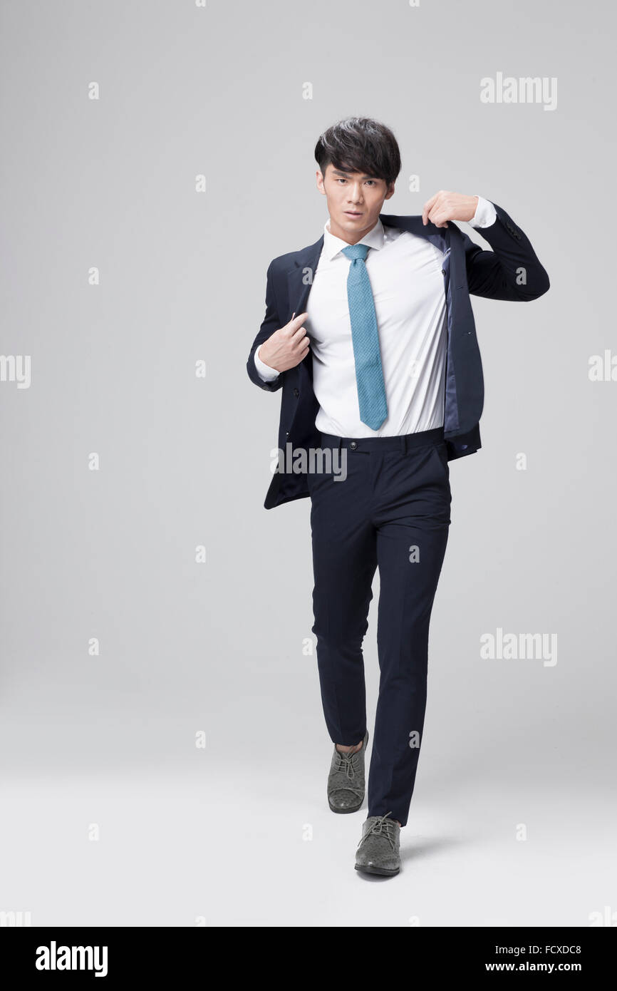 Man in business wear putting on his jacket and walking Stock Photo