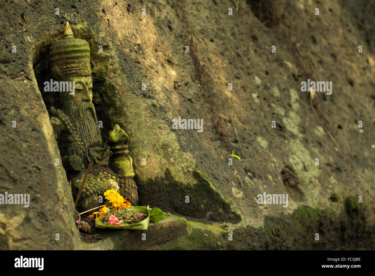 A holy shrine carved into the rock with an offering in Bali, Indonesia. Stock Photo