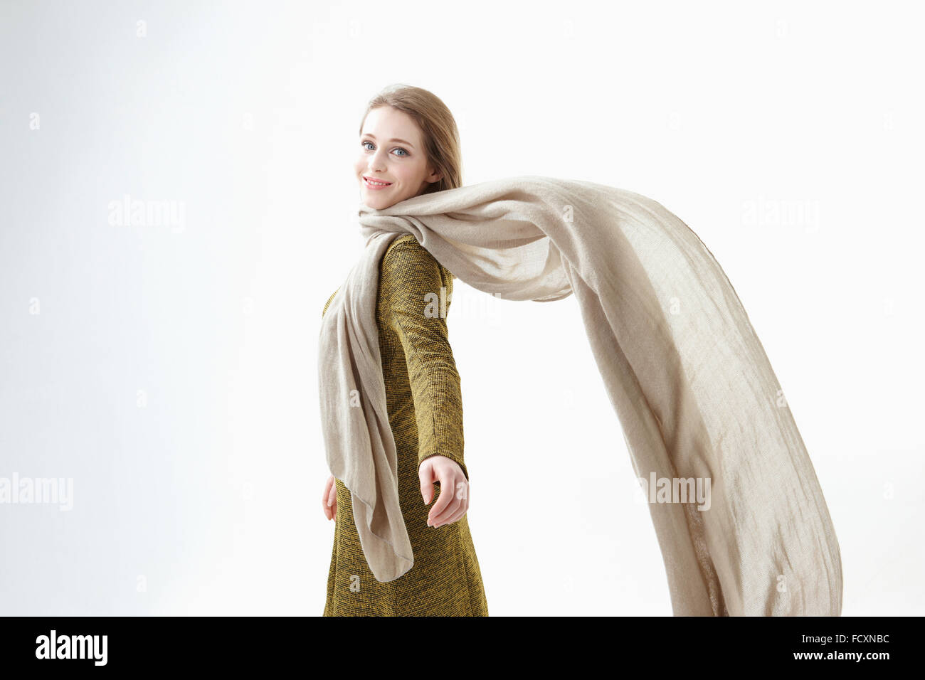 Side view portrait of young smiling woman flapping scarf looking back Stock Photo