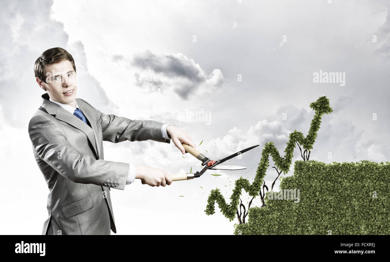 Young businessman cutting bush in shape of graph Stock Photo - Alamy