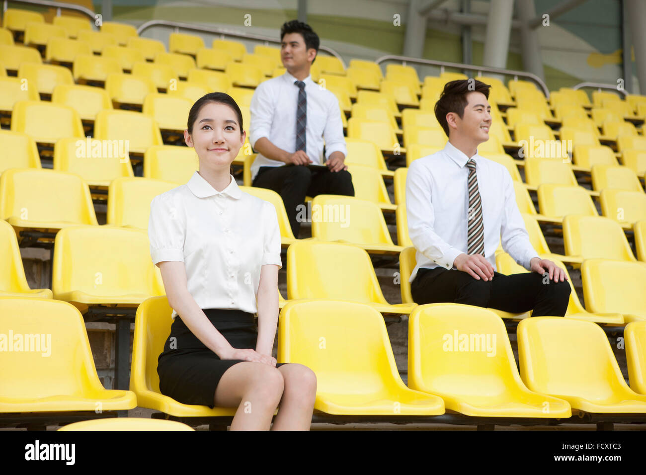 Three business people sitting on stadium seats Stock Photo