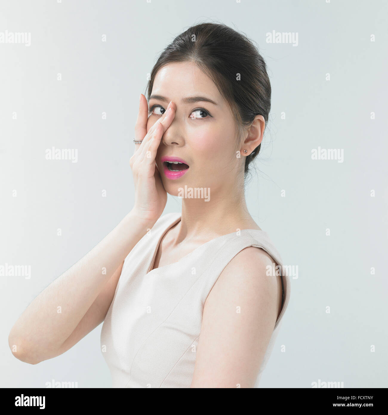 Portrait of young woman with pink lips covering half face looking up Stock Photo