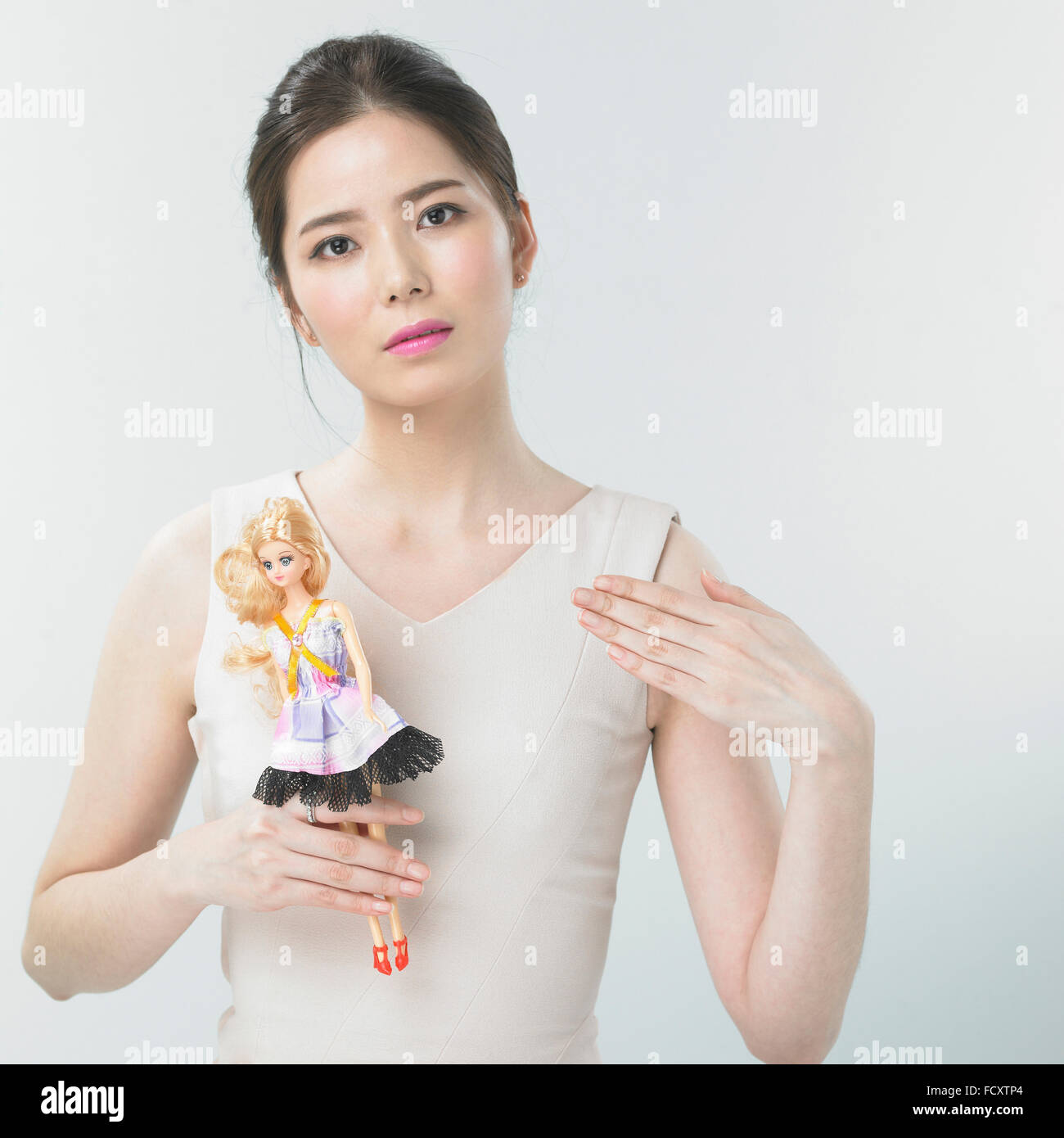 Portrait of yong woman posing with a barbie doll Stock Photo