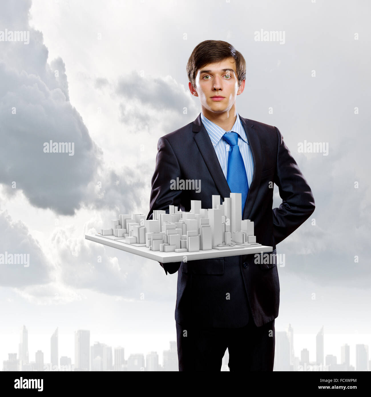 Handsome businessman holding model of modern city Stock Photo - Alamy