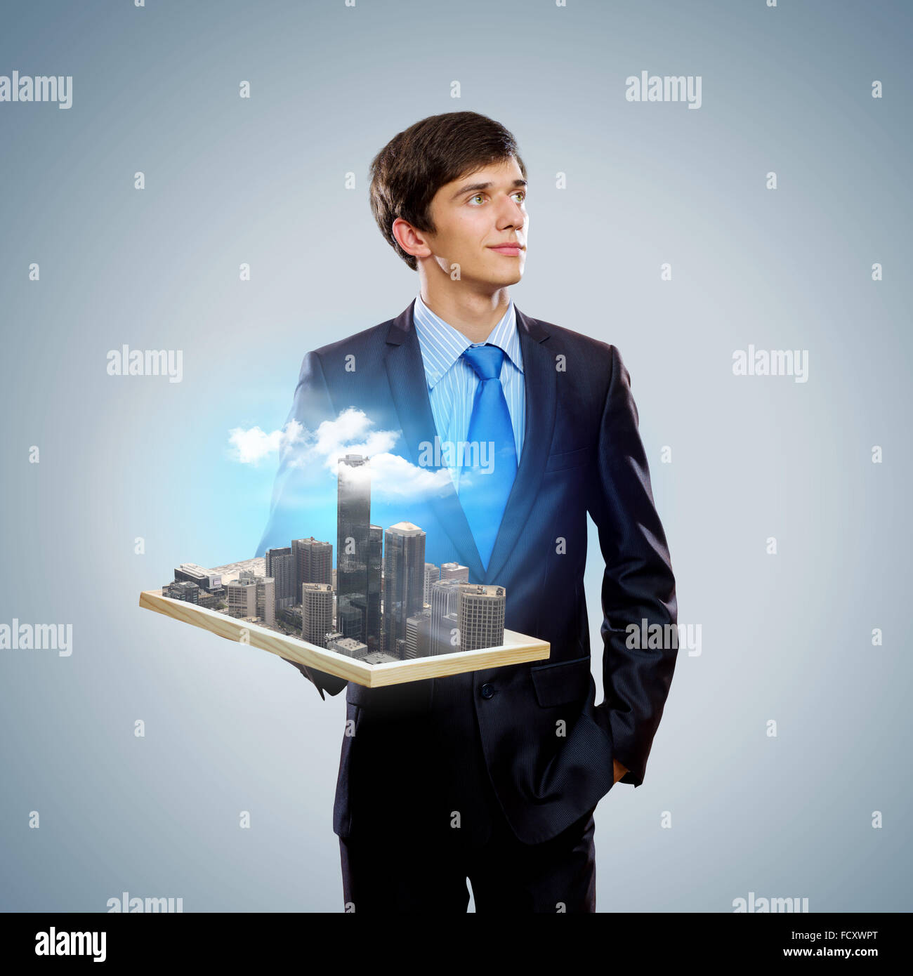 Handsome businessman holding model of modern city Stock Photo - Alamy