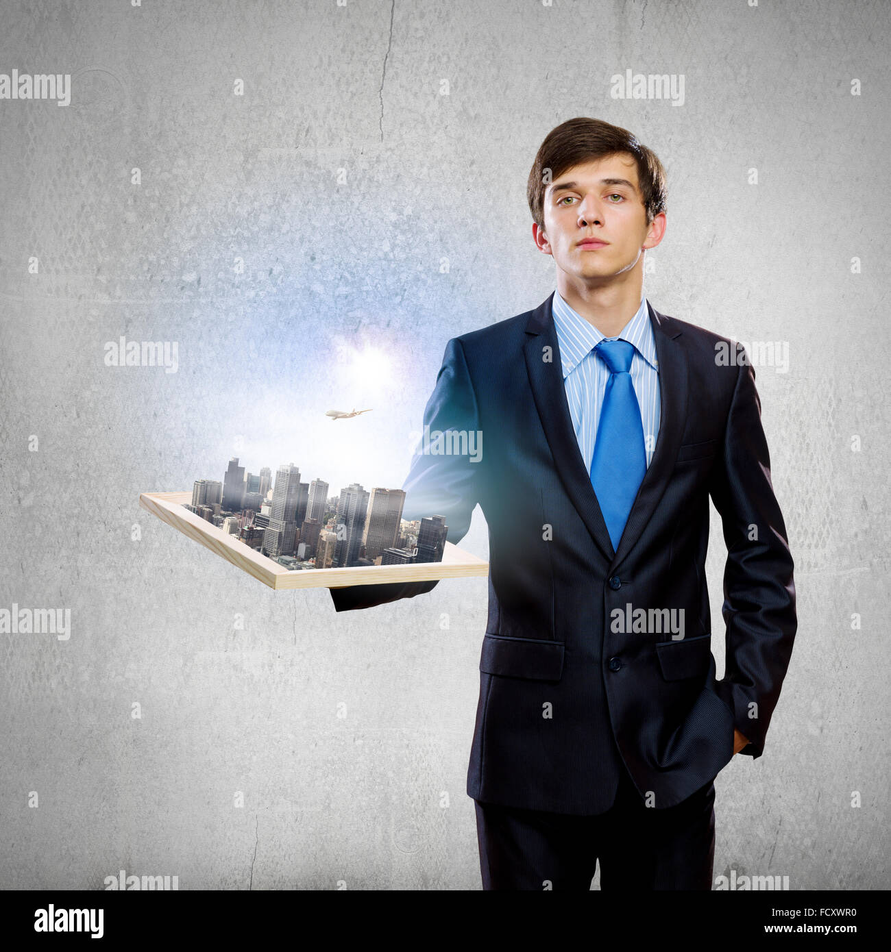 Handsome businessman holding model of modern city Stock Photo - Alamy