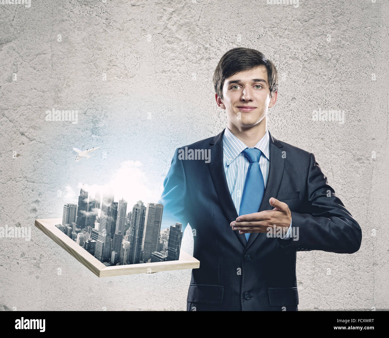 Handsome businessman holding model of modern city Stock Photo - Alamy