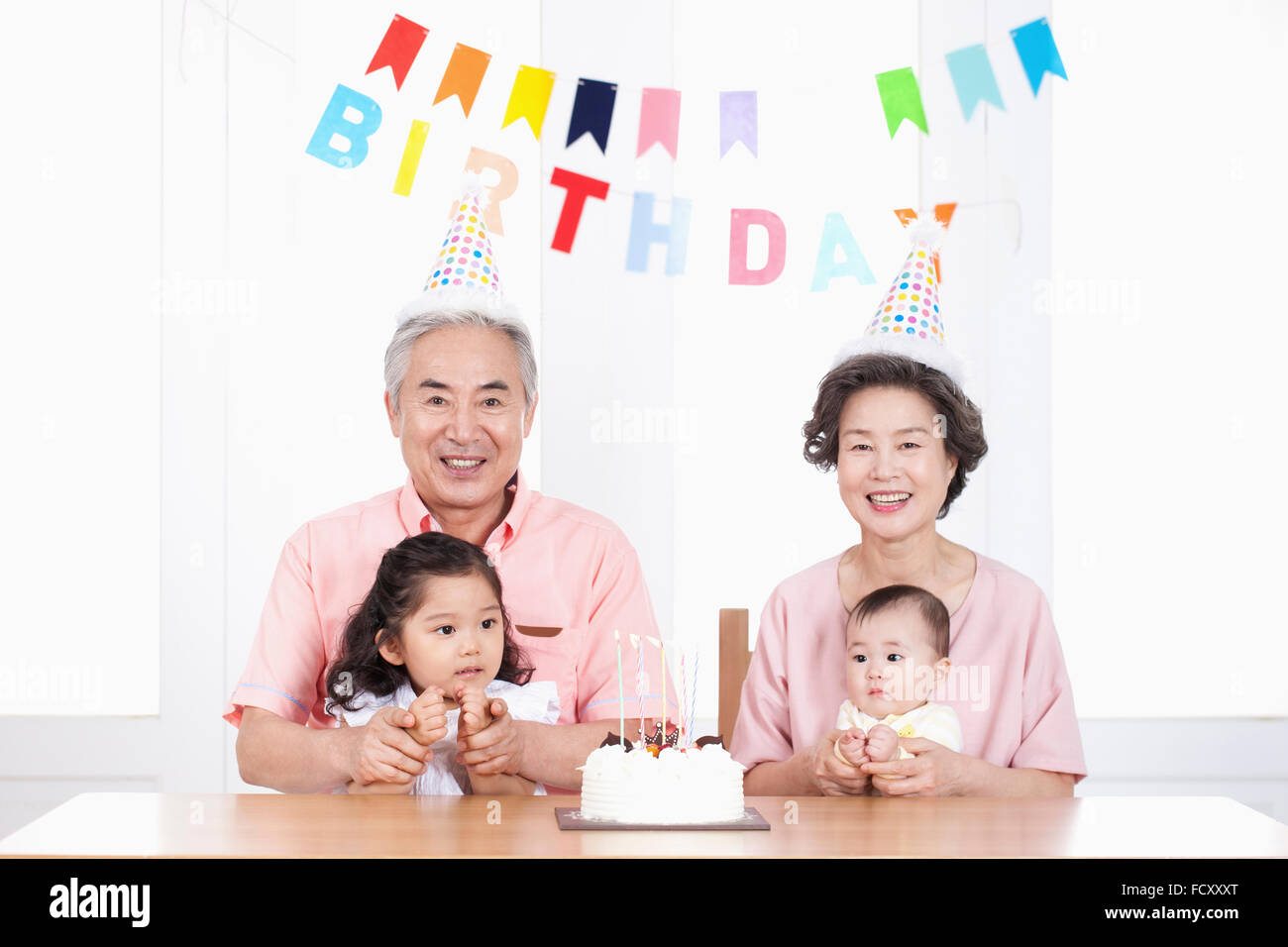 Portrait of old couple with thier grandchidren at birthday party Stock Photo