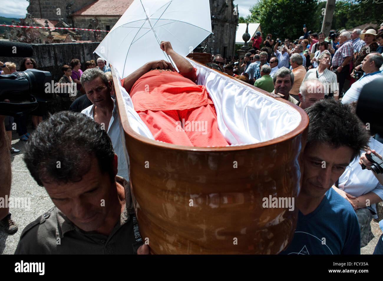 One offered is protected from the sun with an umbrella during the procession of coffins in Santa Marta de Ribarteme (Pontevedra) Stock Photo